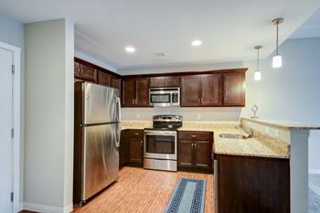 a kitchen with wooden cabinets and stainless steel appliances at Residences at the Street, Washington, PA, 15301